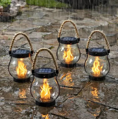 Four rope-handled lanterns glowing on wet paving stones while rain falls around them 2