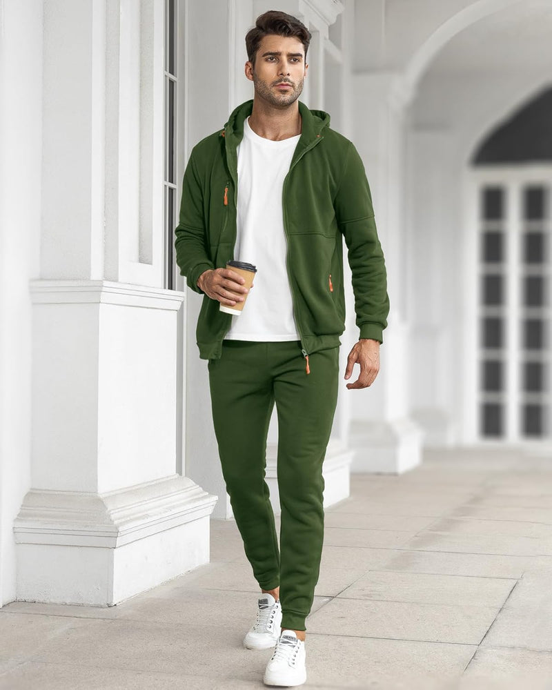 Model walking along a white colonnade in the green set, open jacket over a white t-shirt, holding a coffee 18
