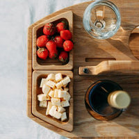 Close-up from above of two snack trays holding strawberries and cheese cubes, with glass and bottle neck nearby 9
