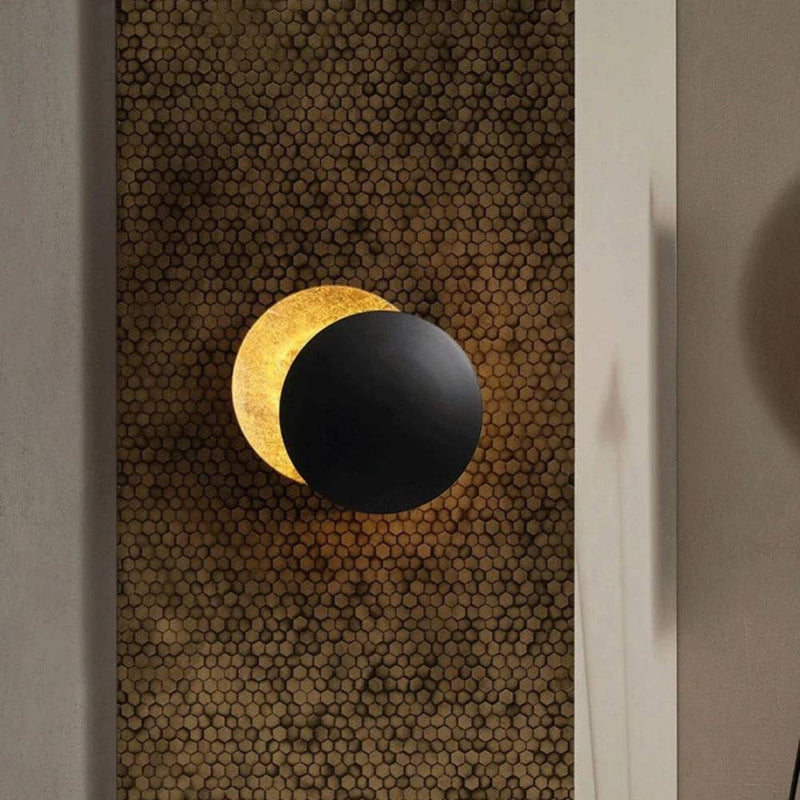 Wall lamp with a black front disc and gold-leaf rear disc, set on a honeycomb-patterned panel 2