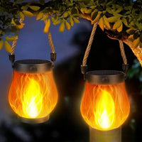 Two glowing lanterns hanging by their rope handles from a tree branch at night 8