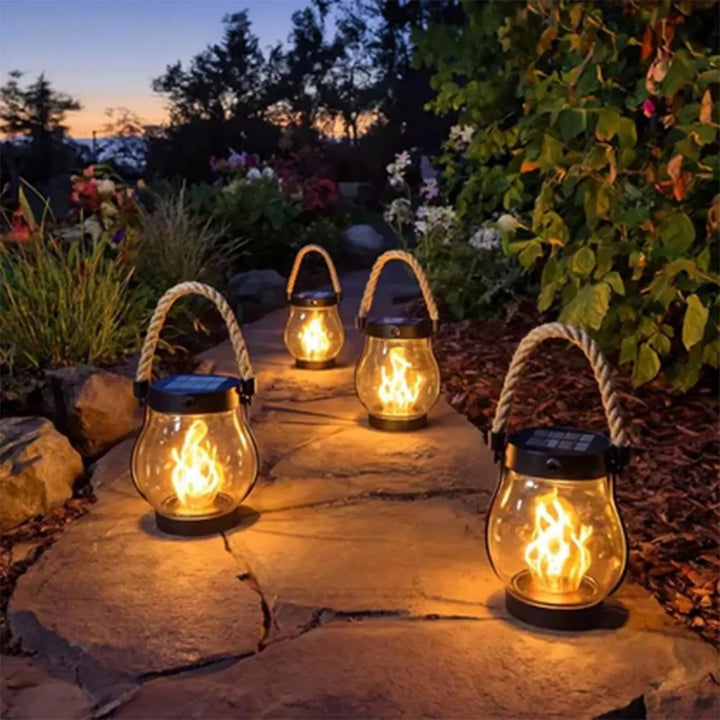 Four lit lanterns placed along a stone garden path at dusk 9