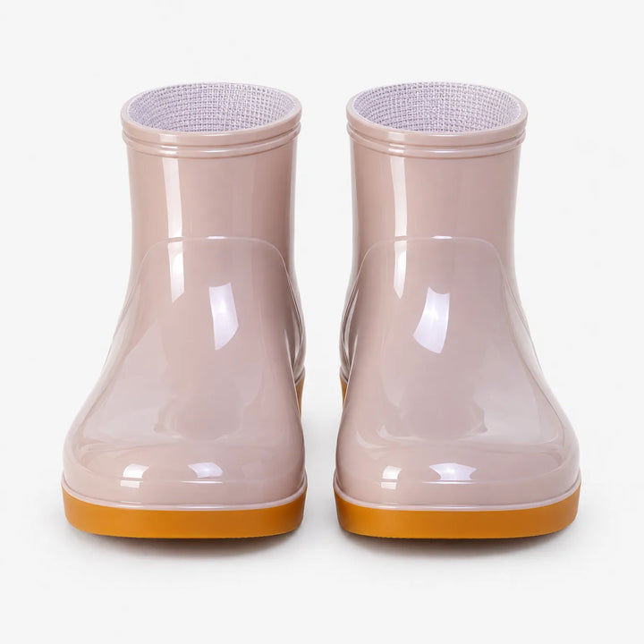 Front view of a pair of pink glossy ankle boots with orange soles and light textured lining. 6