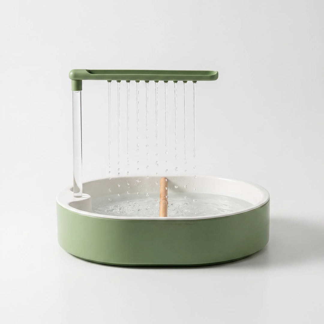 Green and white round bird bath on a plain background, water falling from a row of spouts onto a wooden perch. 1