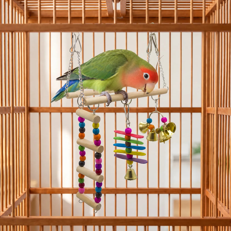 Green lovebird with a red face perching on the wooden bar inside a cage, the beaded ladder, slats and bells hanging beneath. 2