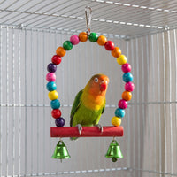 Lovebird perched on a red wooden bar of a beaded arch swing with two green bells inside a cage. 2