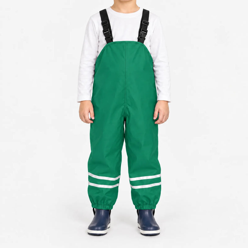 Child facing front in green waterproof dungarees with black adjustable straps, reflective ankle stripes and navy boots, white background. 10