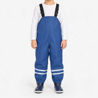 Child facing front in blue waterproof dungarees with adjustable black straps, reflective ankle stripes and navy boots against a white background. 2