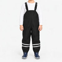 Child facing front in black waterproof dungarees with white long-sleeve top, reflective ankle stripes and navy boots on a white background. 7