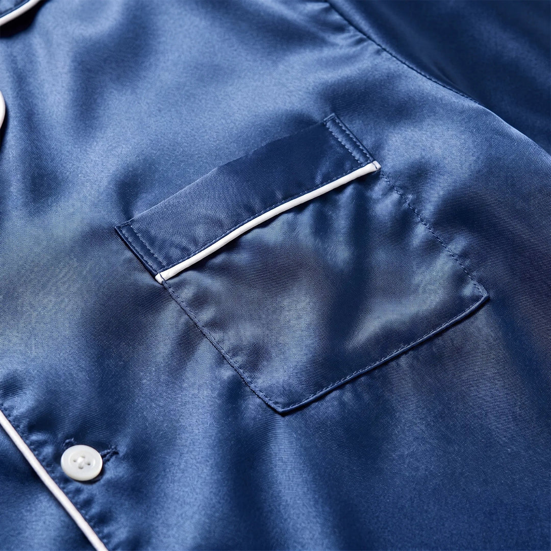 Close-up detail of the navy satin chest pocket with white piped edge, stitching and a pearl-effect button on the placket. 5
