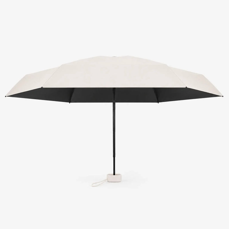 Open cream umbrella shown from the side against white, with a black underside, black shaft and a small cream cord loop at the handle. 4