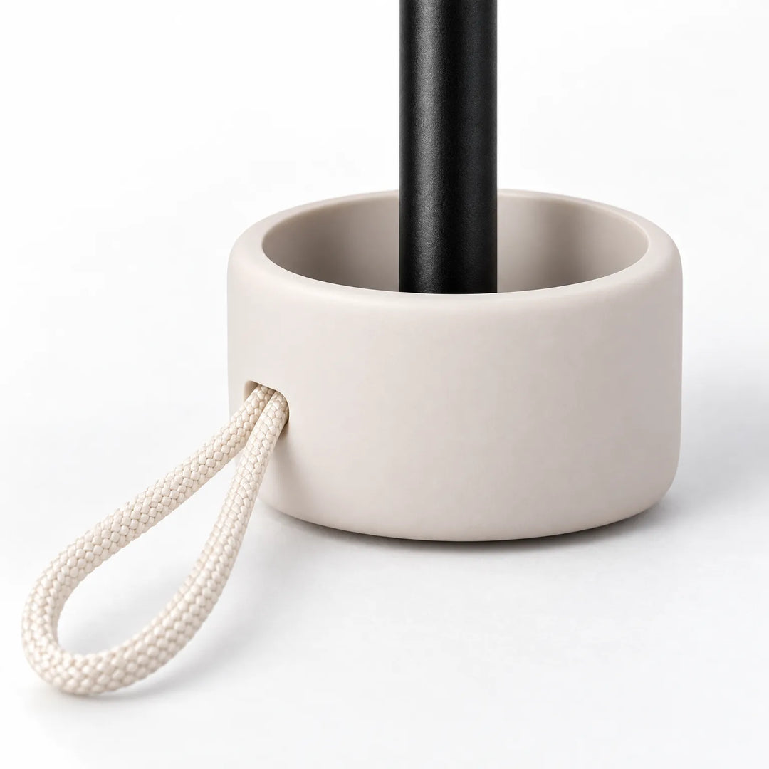 Close-up of the umbrella handle: a rounded cream base around a black shaft, with a braided cream cord loop threaded through. 5