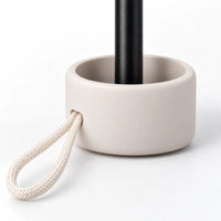 Close-up of the umbrella handle: a rounded cream base around a black shaft, with a braided cream cord loop threaded through. 5