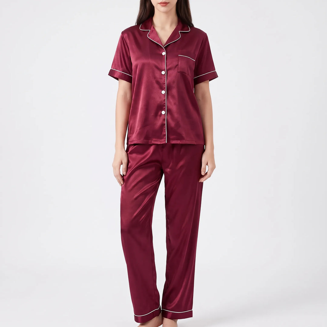 Studio front view of a model wearing the burgundy satin pyjama set with contrast white piping and white buttons. 6
