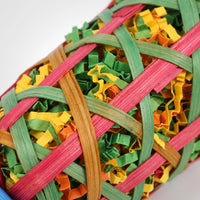 Close-up of the woven pink, green and orange cane strips with colourful shredded paper visible inside the basket. 4