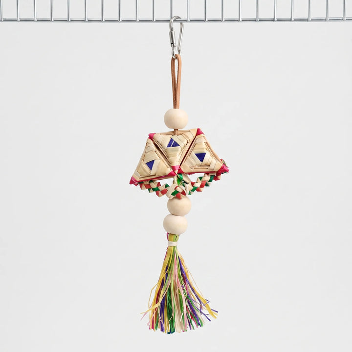 Whole woven toy hanging from a steel clip on a cage wire, with wooden beads, braided straw triangles and a colourful tassel. 1