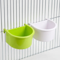 One green and one white half-round bowl hooked onto cage bars, shown at an angle to reveal their depth. 6