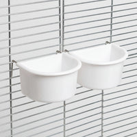 Two white bowls hanging on a metal cage grille, seen from an angle with thin metal hooks over the bars. 7
