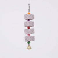 Four porous grey stone blocks strung with orange, purple, red, pink and green wooden beads, a clip above and a brass bell below, on plain background. 1