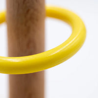 Close-up of a smooth yellow plastic ring resting around the wooden peg, showing the glossy finish against a plain white background. 4