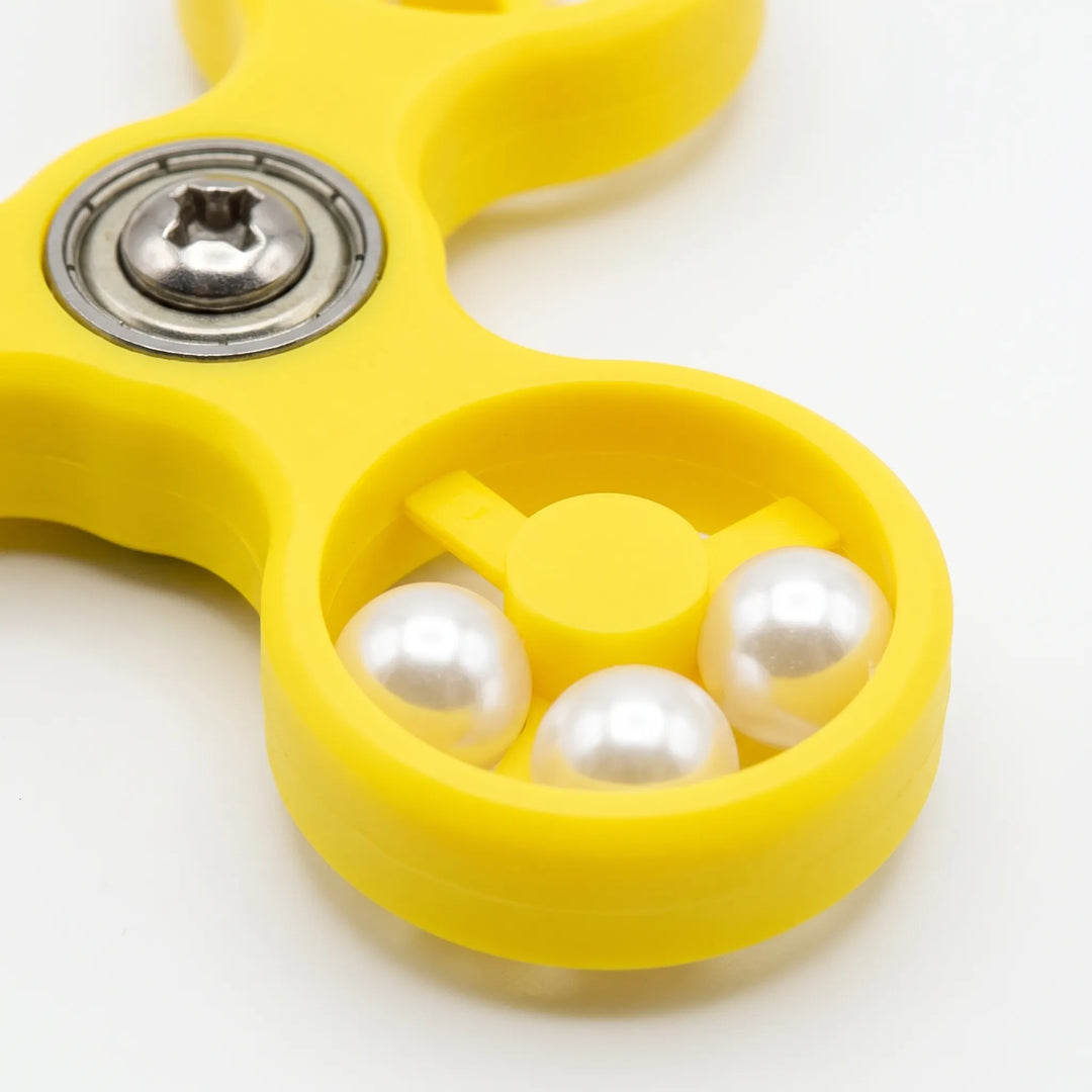 Close-up of one spinner ring holding three white pearl beads, beside the metal bearing and screw at the centre. 4