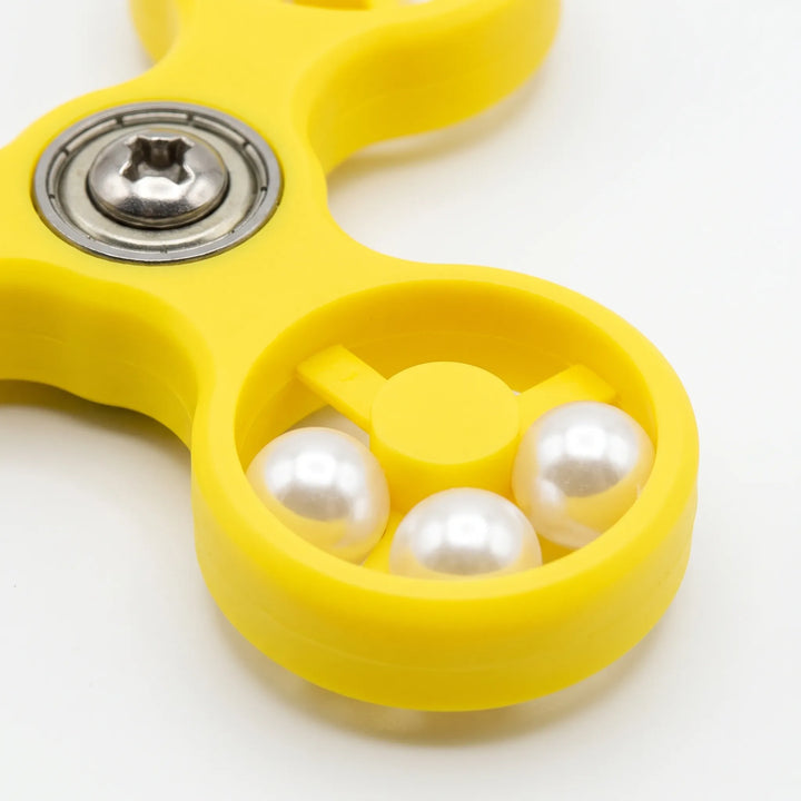 Close-up of one spinner ring holding three white pearl beads, beside the metal bearing and screw at the centre. 4