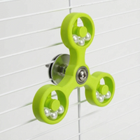 Lime green version of the spinner toy mounted on white cage bars, showing its metal fixing hardware at the back. 6