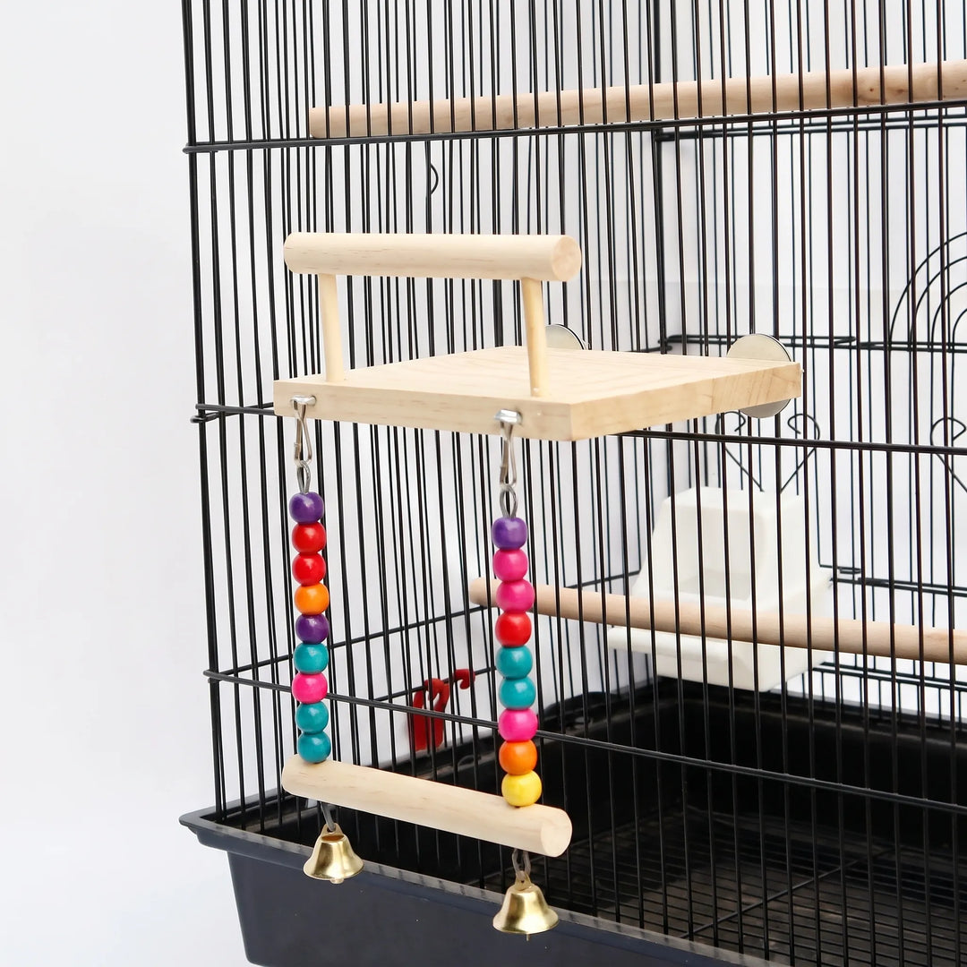 Wooden bird platform with perch rail and a bead-and-bell swing below, fixed to the bars of a black cage. 1