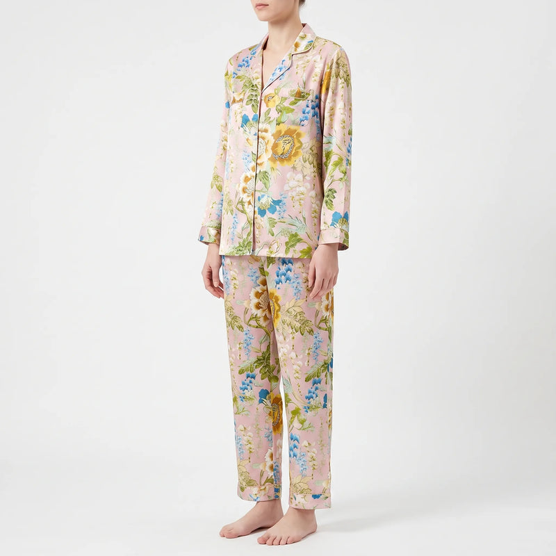 Three-quarter side view of the pyjama set on a model, showing two chest pockets, piped cuffs and the pink floral satin trousers. 3
