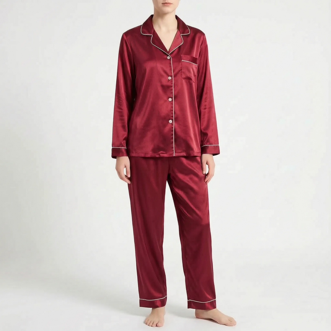 Front view of the burgundy satin pyjama set with pale piping and buttons, worn by a model. 10