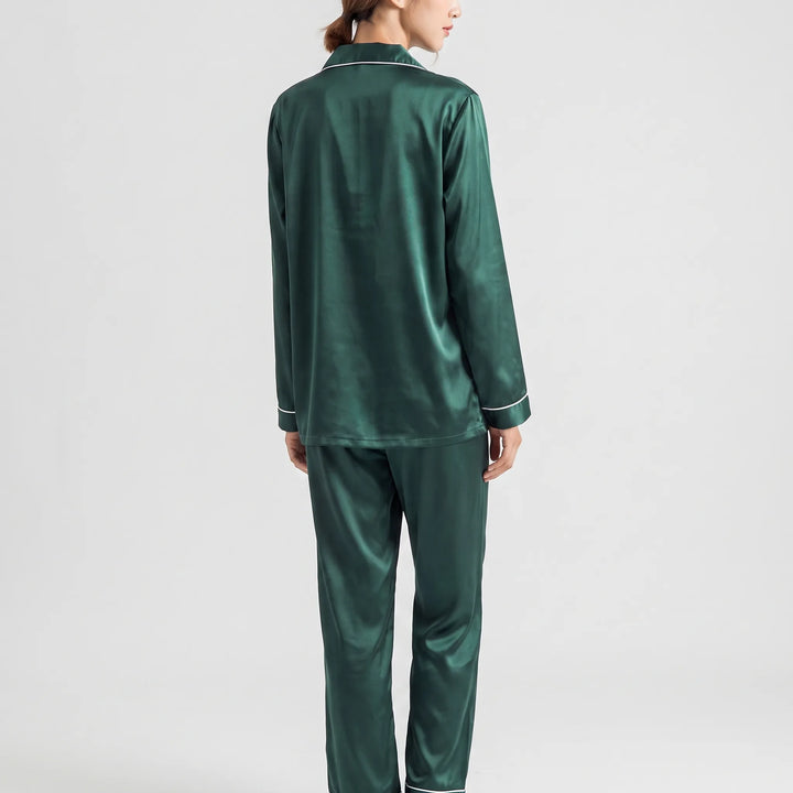 Back view of the green satin pyjama set on a model, showing the smooth shirt back and white-piped cuffs. 3