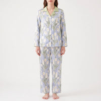 Front view of a model standing in the blue pyjama set with cream tulip print, green collar and wide straight trousers. 8