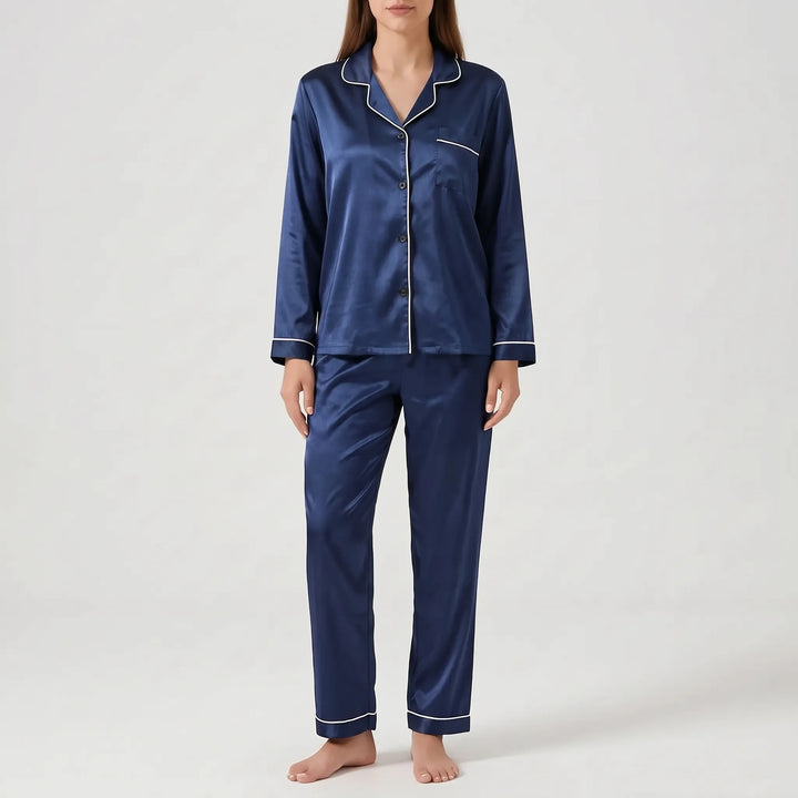 Model wearing the satin pyjama set in navy blue with white piping and dark buttons, front view. 12