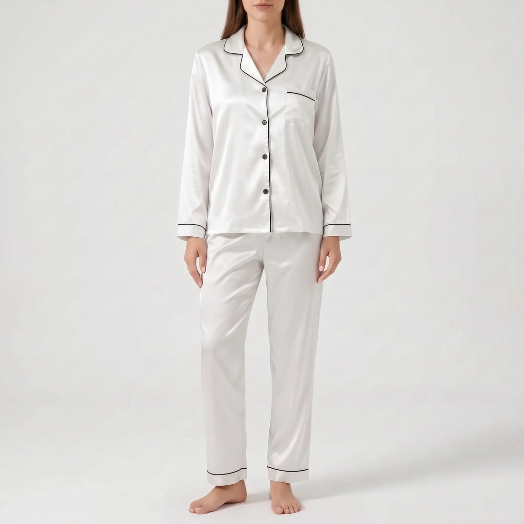Model wearing the satin pyjama set in white with black piping and dark buttons, front view. 6