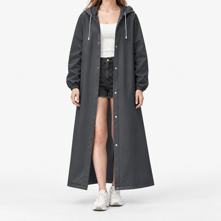 Studio front view of the dark grey hooded raincoat worn open with silver snap buttons and white drawstrings over black shorts. 11