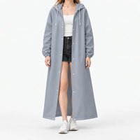 Studio front view of the grey-blue hooded raincoat worn open with white snaps and drawstrings over a white top and shorts. 8