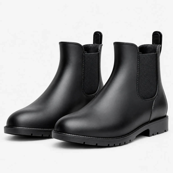 Pair of matte black Chelsea rain boots with elastic side panels and pull tabs, shown at an angle on white. 2
