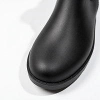 Close-up of the rounded toe of a black rain boot, showing its textured matte surface and stitched edge above the sole. 6