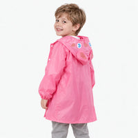 Back view of a smiling boy in the pink rain jacket, showing the rabbit hood with printed eyes and ears. 4