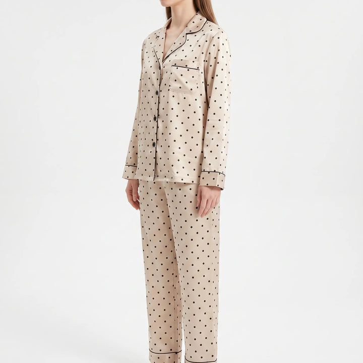 Three-quarter front view of a model in the pyjama set, showing the chest pocket, black buttons and piped cuffs and trouser hems. 4