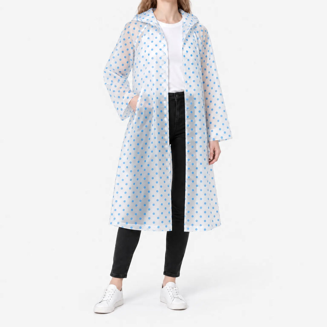 Model in the translucent blue polka dot raincoat worn open over a white tee, one hand in a pocket, studio shot. 2