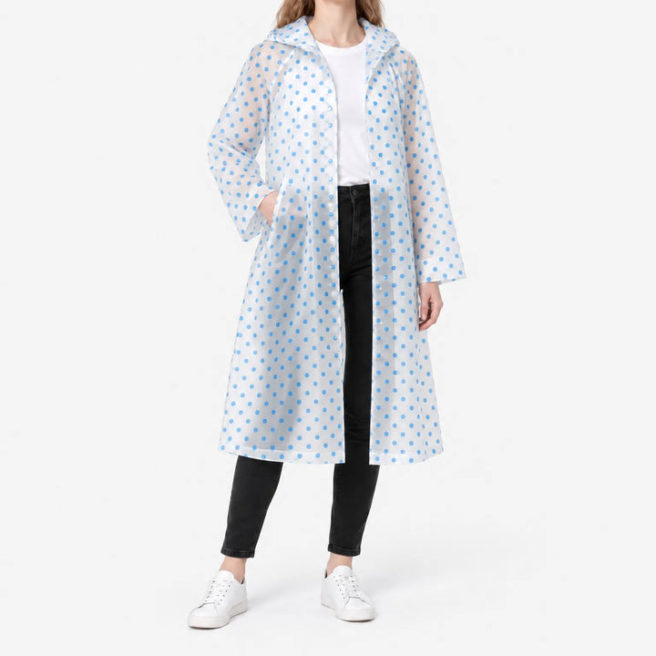 Model in the translucent blue polka dot raincoat worn open over a white tee, one hand in a pocket, studio shot. 2