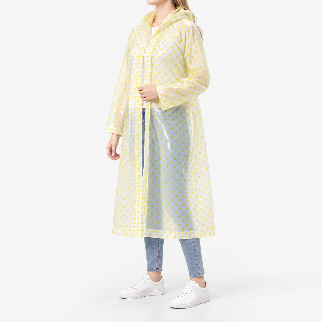 Side view of the translucent yellow polka dot raincoat worn open over jeans, with snap buttons down the front. 5