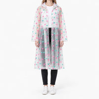 Model wearing the translucent raincoat with pink and teal heart print, front view with snap buttons partly fastened. 7