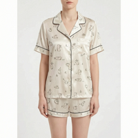Front view on a model of a cream short pyjama set with a line-drawn rabbit print and dark piping. 7