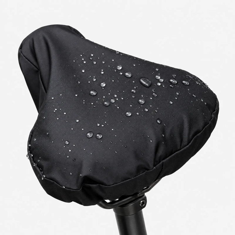 Black saddle cover on a seatpost against a white background, with water droplets beading on the smooth surface. 2