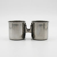 Pair of steel cups with their clips pressed together between them, shown from the front on white. 7