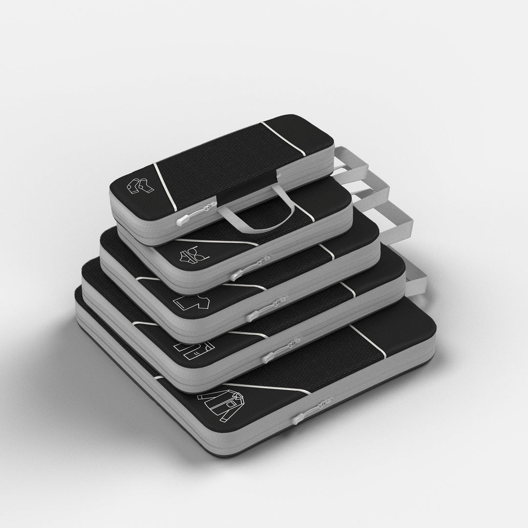 Stack of five black compression packing cubes with grey zip edges, seen from above at an angle 1