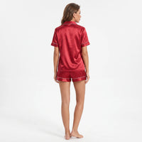 Back view of a model in the red satin pyjama shirt and shorts, showing the plain back and piped hems. 3