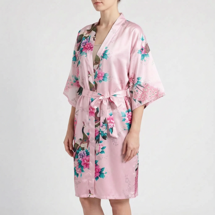 Model wearing the kimono robe in pink satin with peacock and peony print, belt tied at the waist. 6